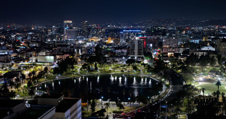 Aerial shot of MacArthur Park Lake overlooking Los Angeles, California cityscape on a clear Summer night. with park lighting