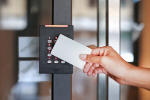 Door access control - young woman holding a key card to lock and unlock door for campus safety. 