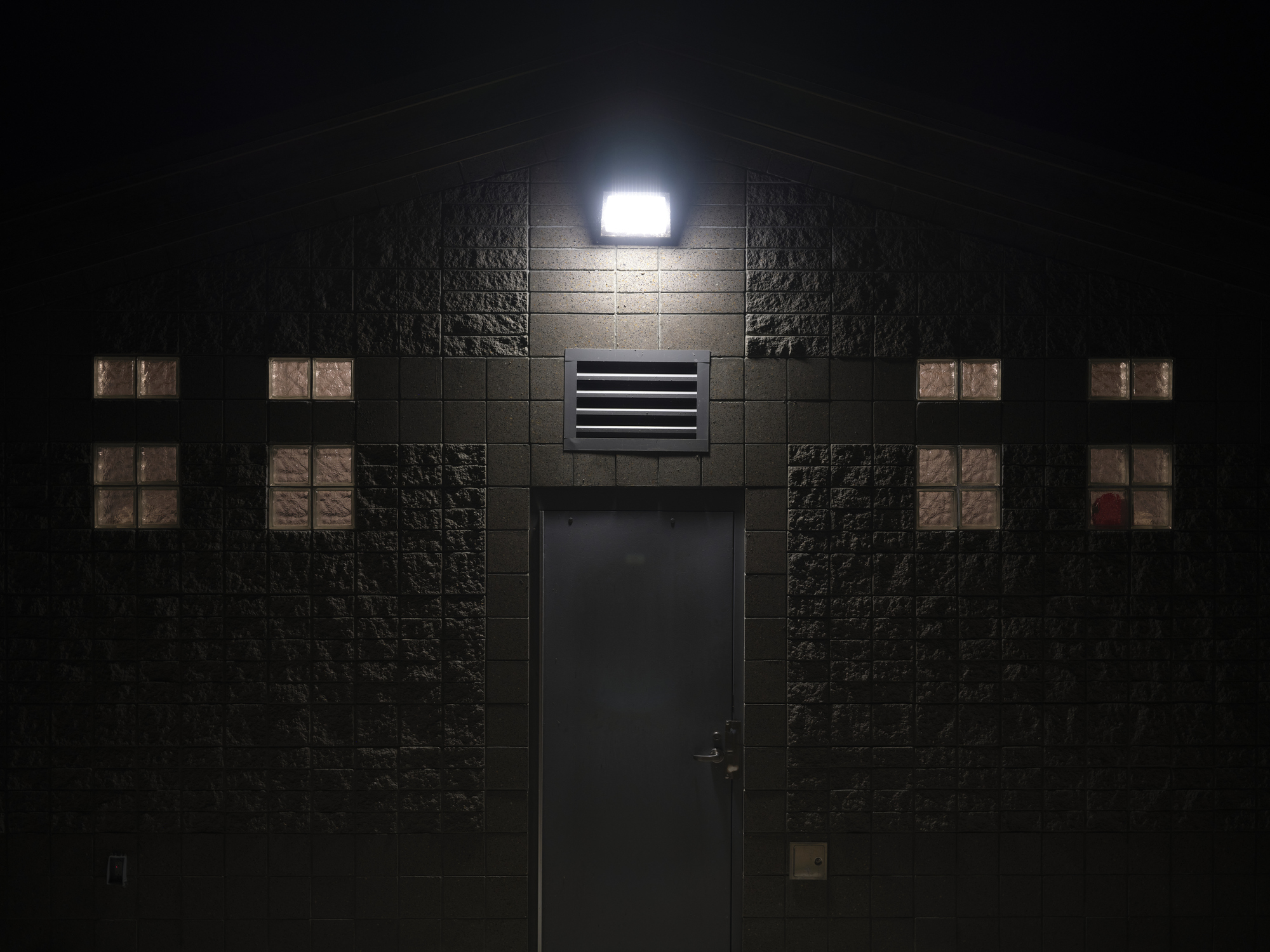 Floodlight illuminating outside of a structure at night on a cold winter day in a park